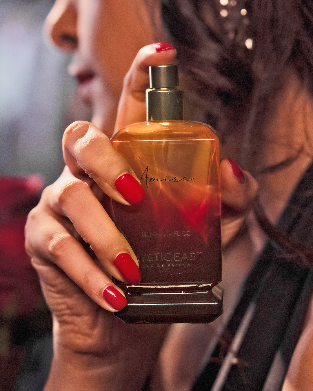 Hand holding a perfume bottle with a blurred background