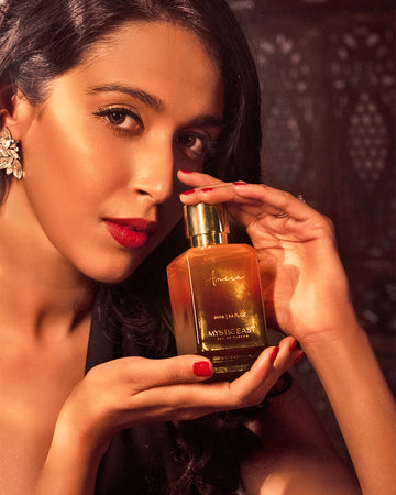 Woman holding a gold bottle of perfume with a dark background